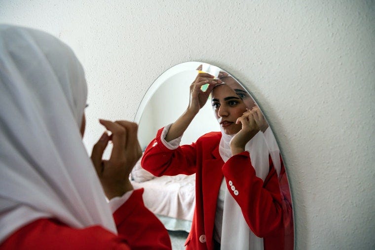 A woman fixes her scarf in a mirror.
