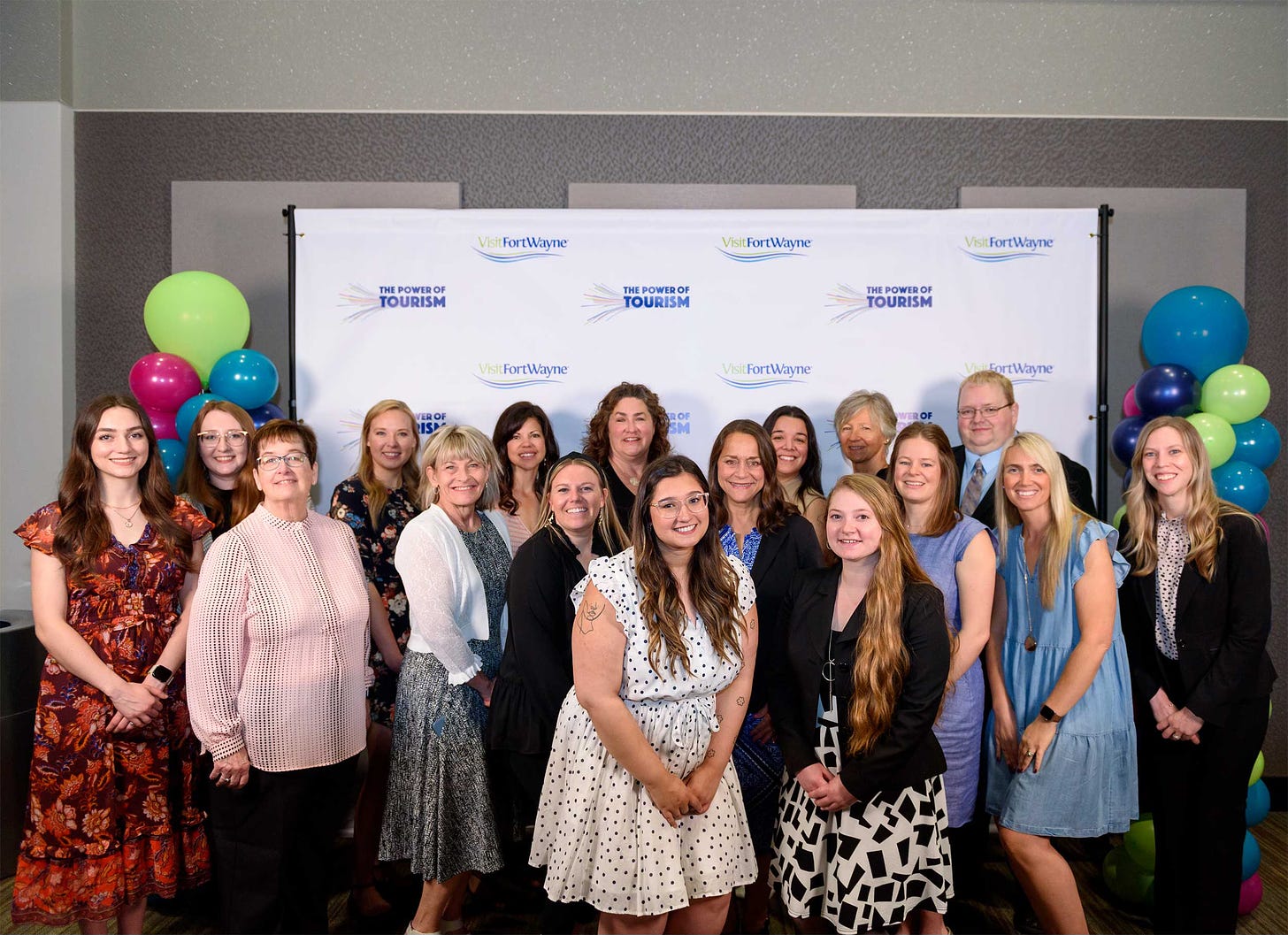 Group of staff members in front of a Visit Fort Wayne logo banner.