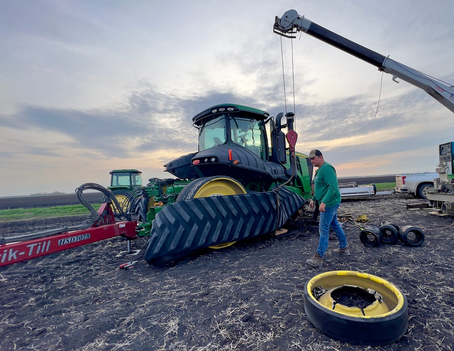 A crane removes a track from a tractor with a broken wheel