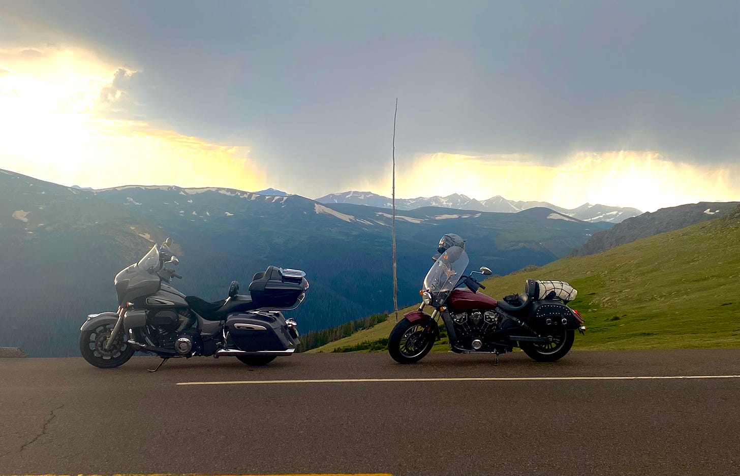 Image of two motorcycles against a mountain backdrop with rain clouds in the distance