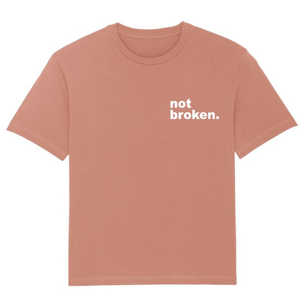 A caramel coloured t shirt has the print on the left hand chest that says not broken in lower print