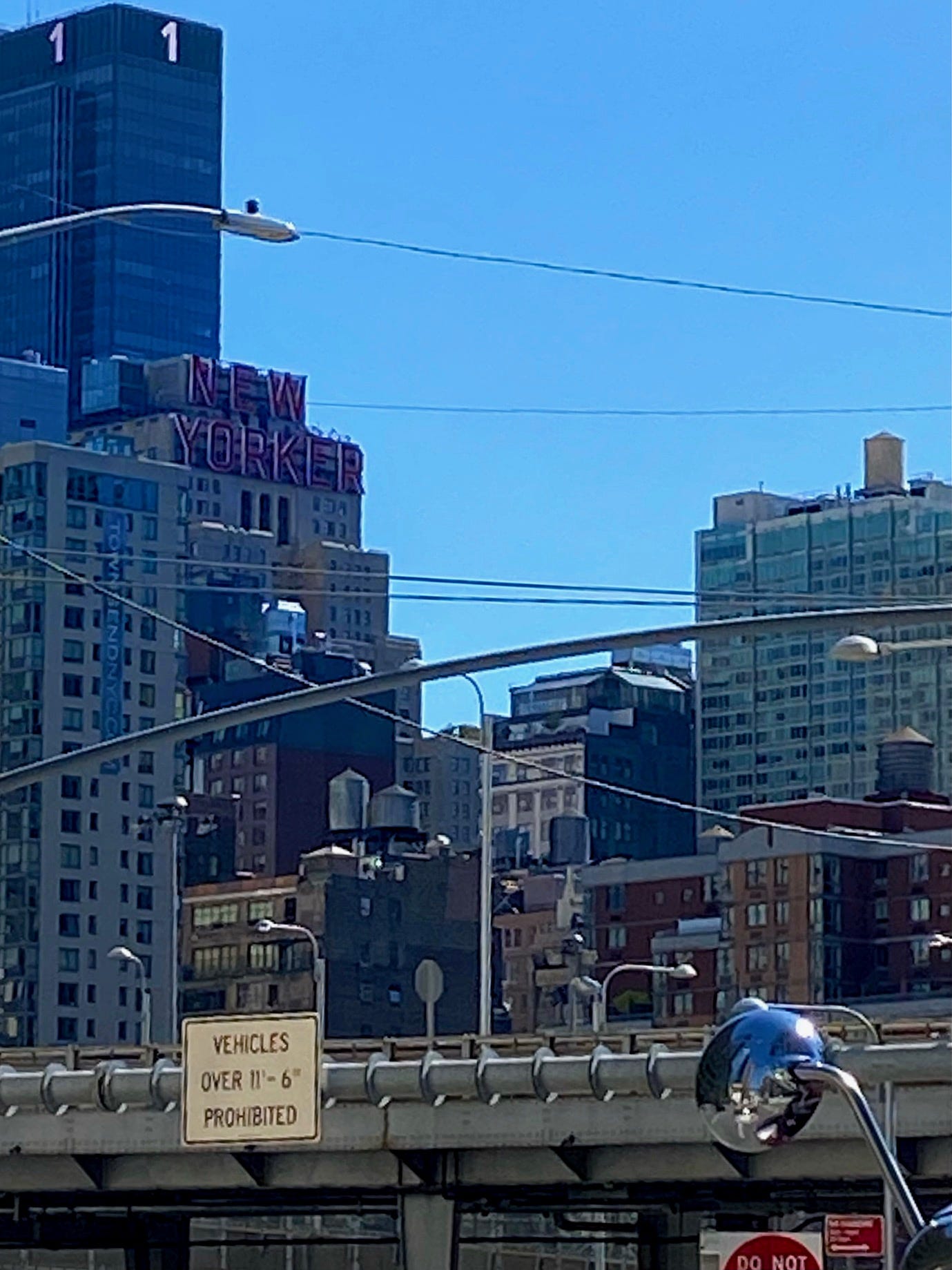 Six water towers are scattered across the roofs of varying heights in front of the New Yorker hotel. 1 Penn Plaza is visible behind it.