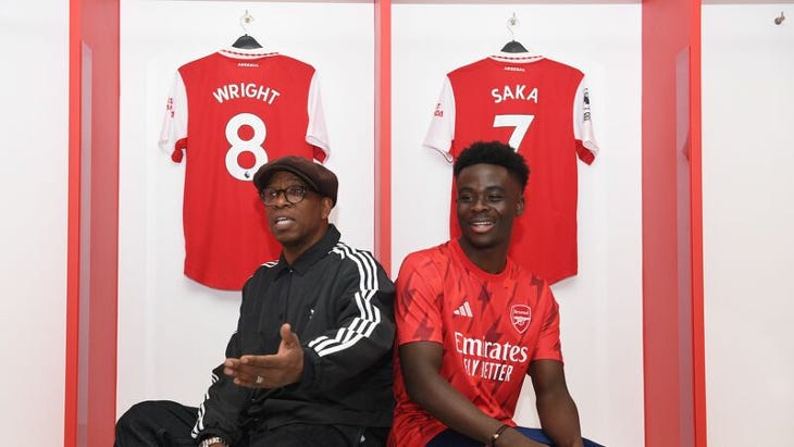 Ian Wright and Bukayo Saka sitting in front of their Arsenal shirts