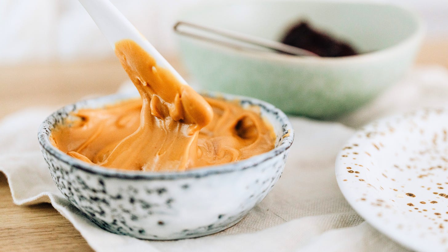 A knife dipped into a bowl of creamy peanut butter