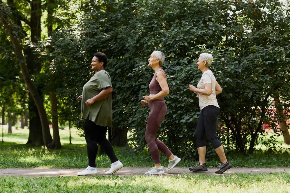 Active senior women jogging in the park outdoors & enjoying sports.