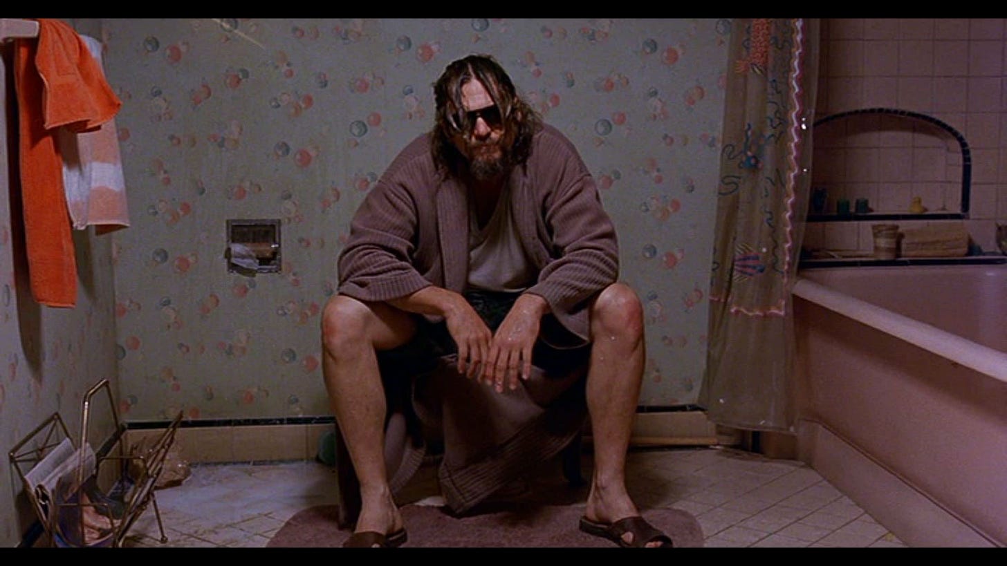 Jeff Bridges, wearing a bathrobe, on a toilet in a scene from The Big Lebowski