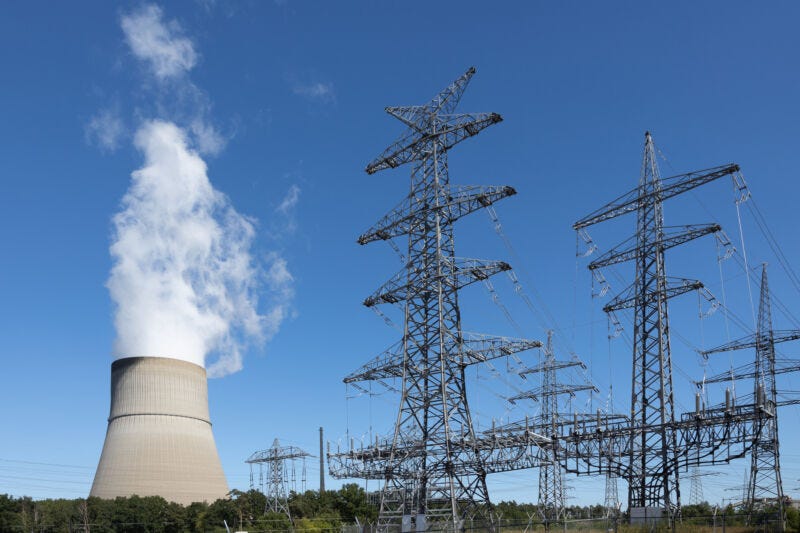 Image of electric power lines with a power plant cooling tower in the background. Image of electric power lines with a power plant cooling tower in the background.
