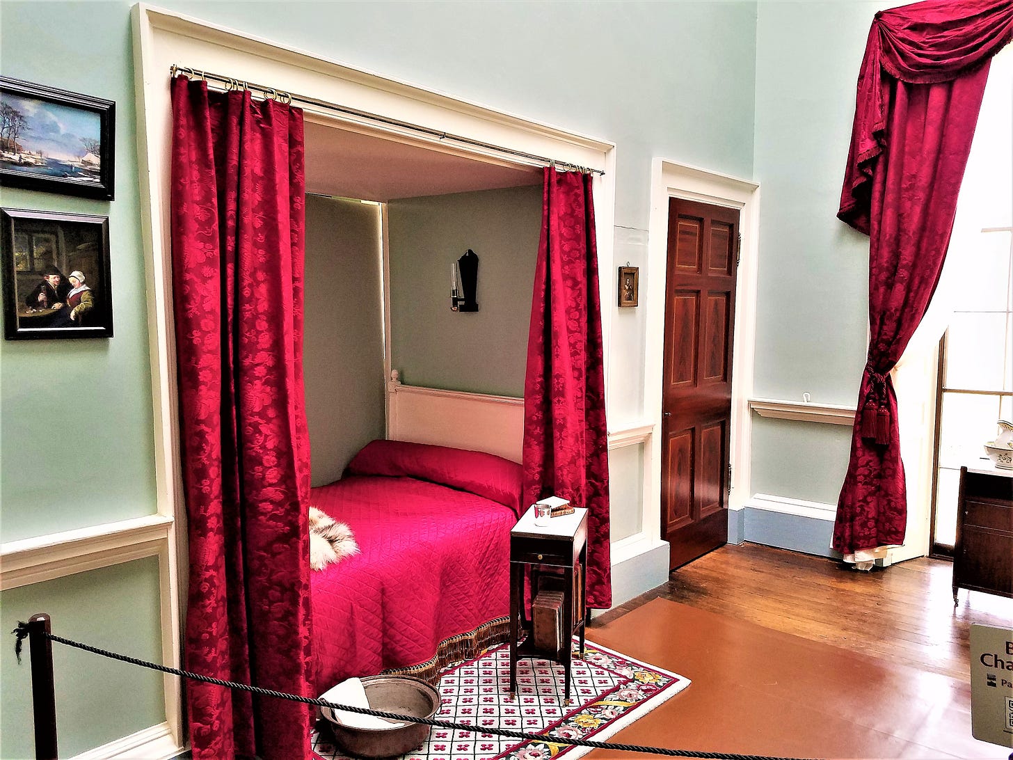Red curtains hang beside a bed built into the wall for Thomas Jefferson.