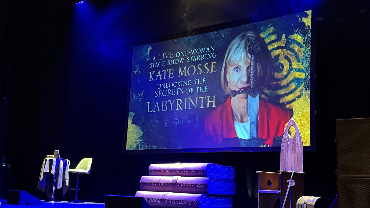 A photograph of a theatre stage with a screen with a large portrait of a caucasian woman. A photograph of a theatre stage with a screen with a large portrait of a caucasian woman.