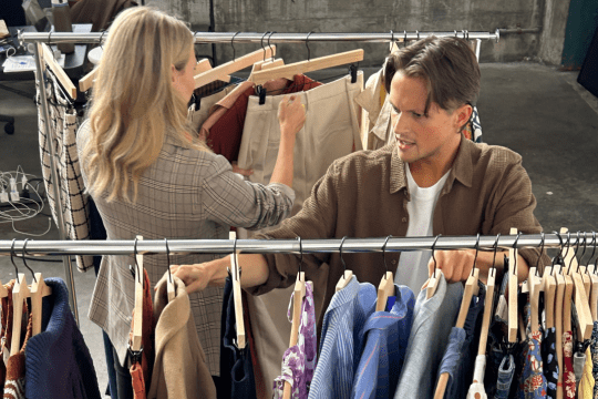 A man and women Stitch Fix stylist picking clothing from a rack.