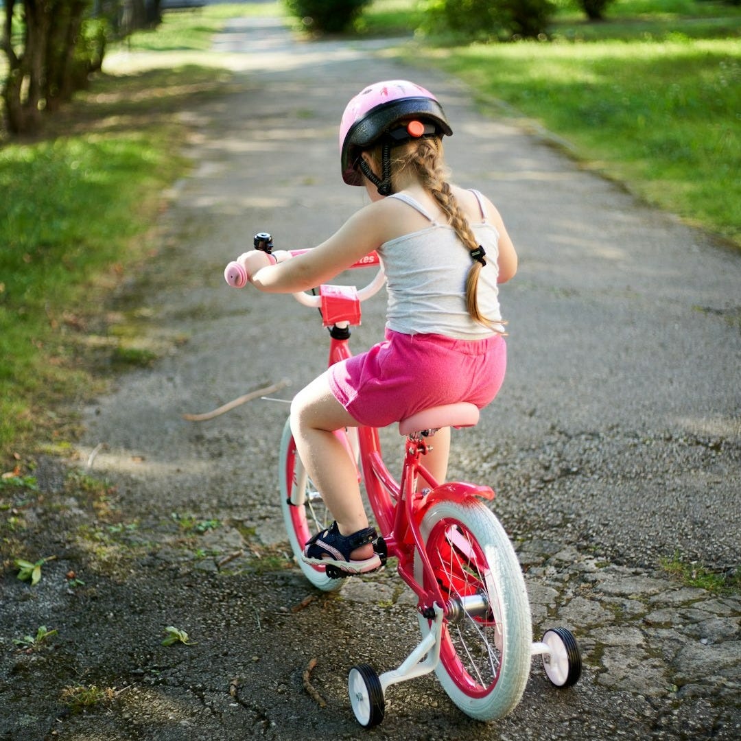a little girl riding a pink bike down a dirt road a little girl riding a pink bike down a dirt road