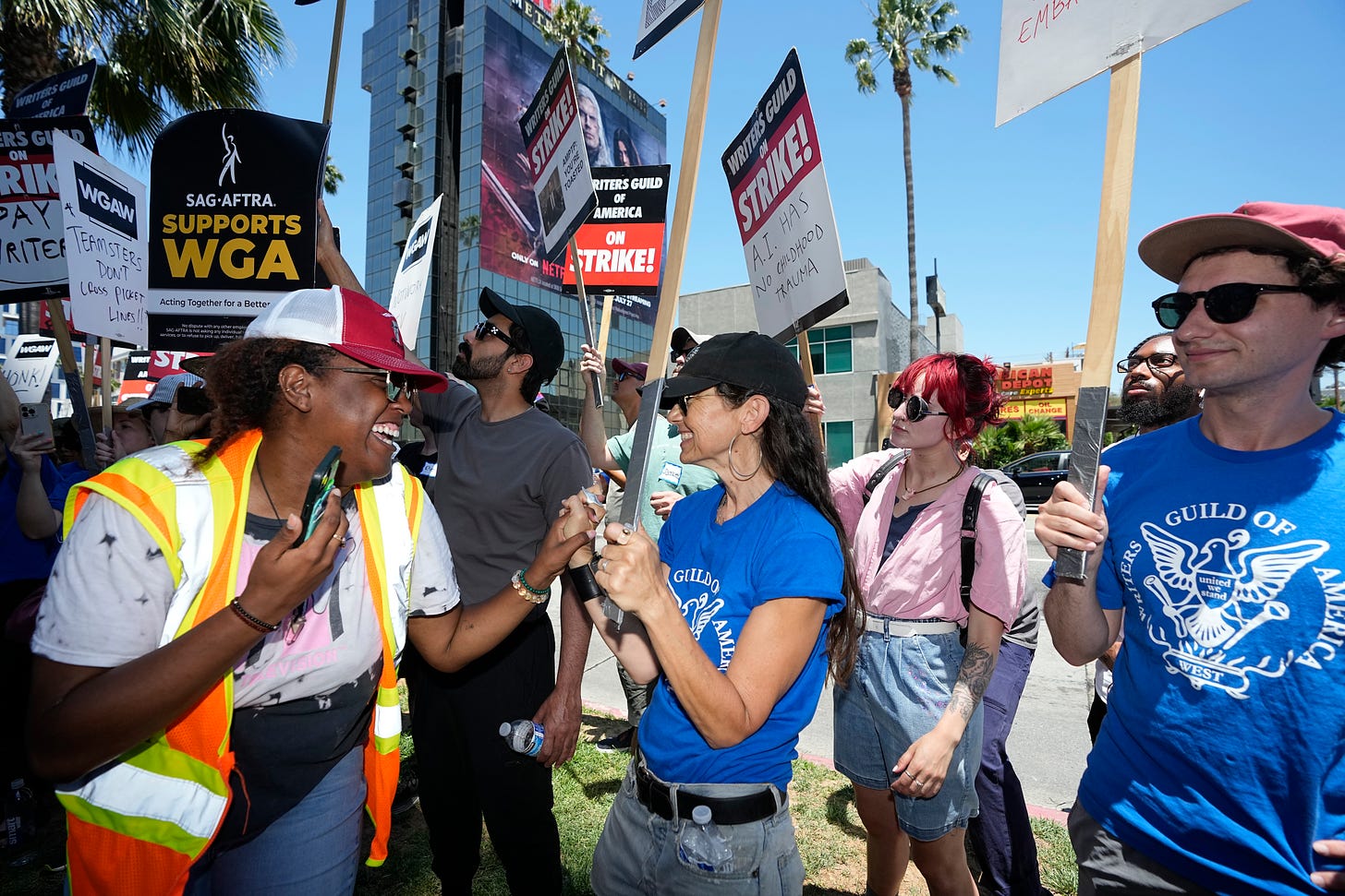 Justine Bateman, center, and Oneika Barrett, left, celebrate outside Netflix during a Writers Guild rally as a strike by The Screen Actors Guild-American Federation of Television and Radio Artists is announced on Thursday, July 13, 2023, in Los Angeles.