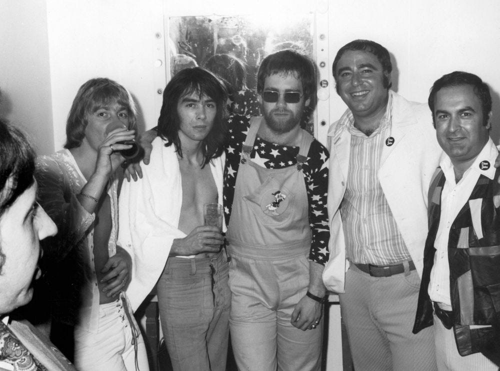 Backstage at the Troubadour following Elton's debut on August 25, 1970. Pictured L-R: Norm Winter (publicist), Dee Murray, Nigel Olsson, Elton, Russ Regan (UNI Records President), Rick Frio (UNI Marketing Manager)  (Photo Courtesy of Rick Frio)