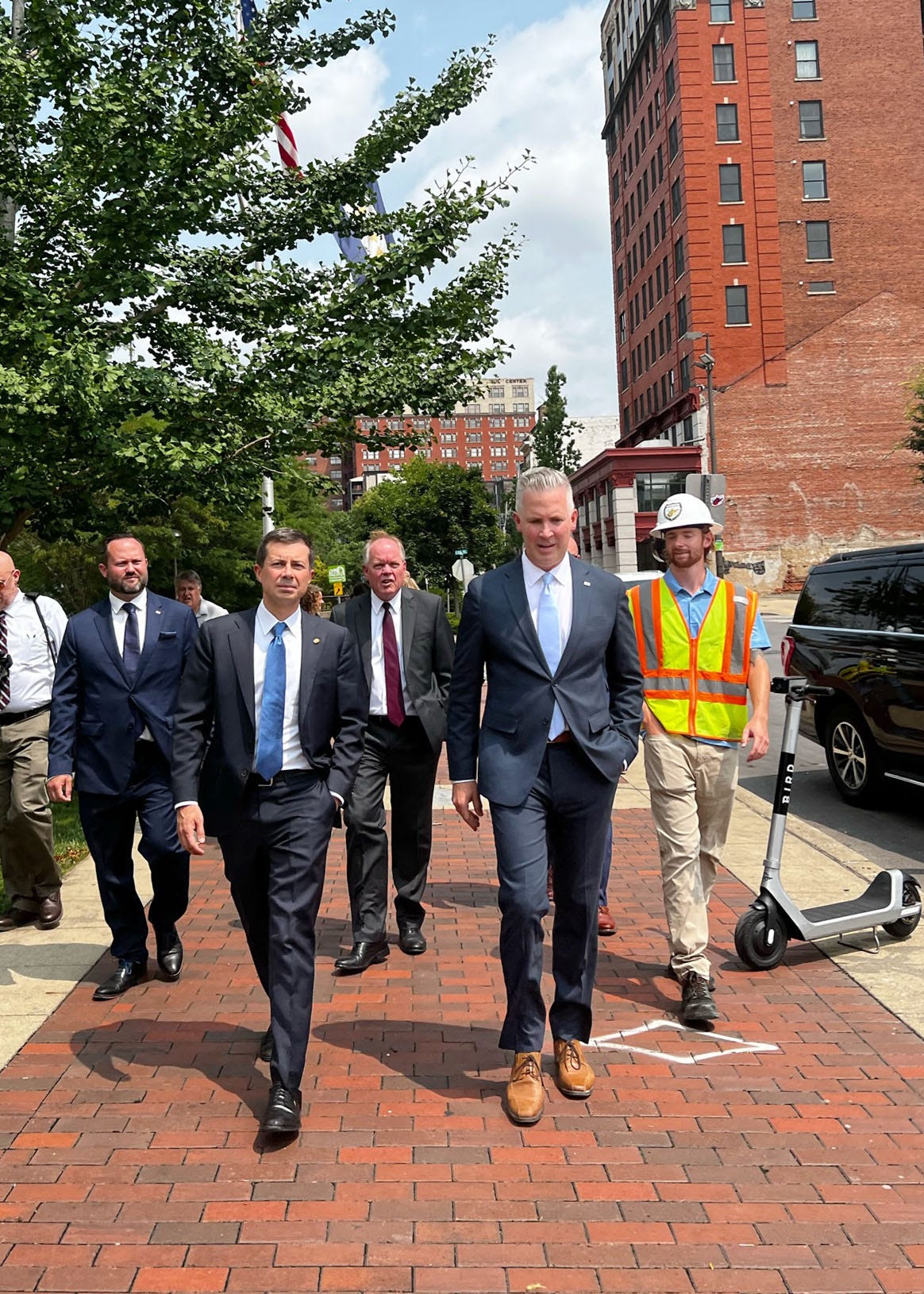 Photo of Secretary Pete Buttigieg, Mayor Glenn Elliott and other city officials touring the streets of downtown Wheeling, West Virginia.