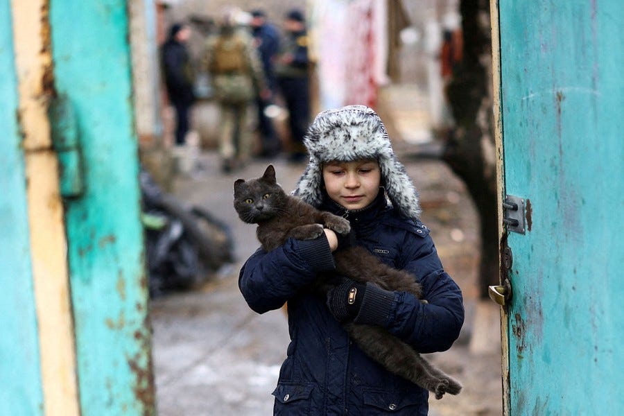 A boy carries a cat while evacuating his house.