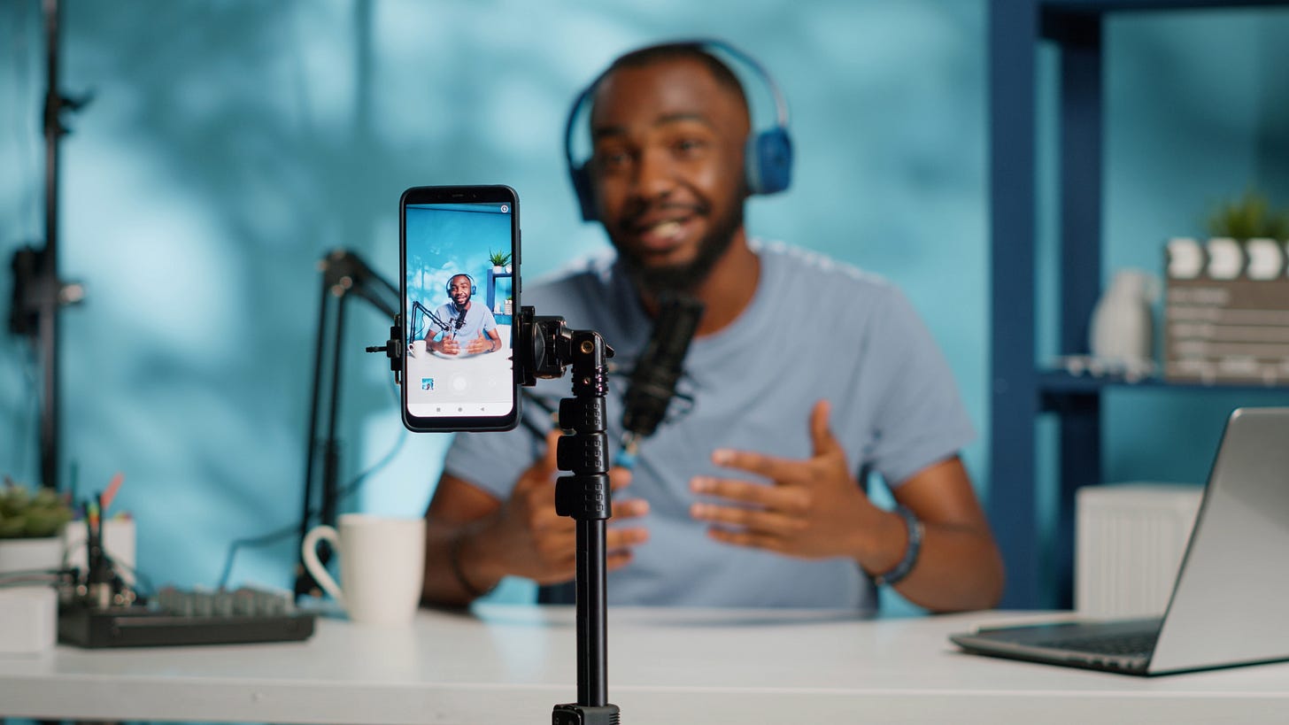 A Black man creates a video for his business as part of a zero click content strategy. He's using his cell phone to record a video to post to social media.