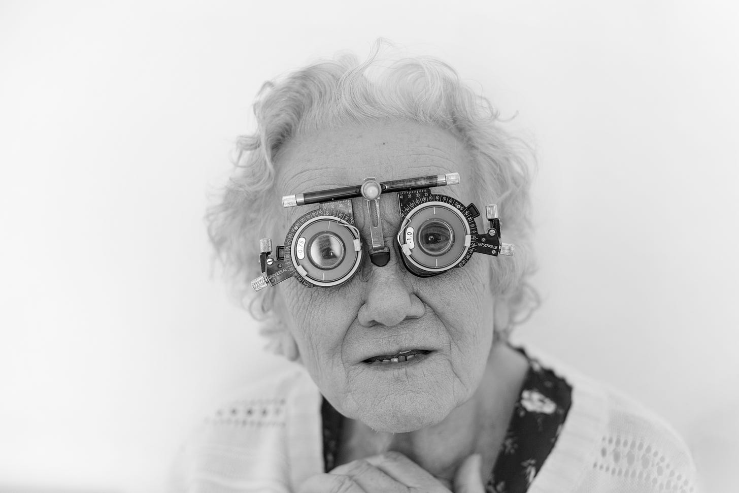 An elderly looking lady looks at the camera wearing a very strange pair of glasses designed to help test eyesight.
