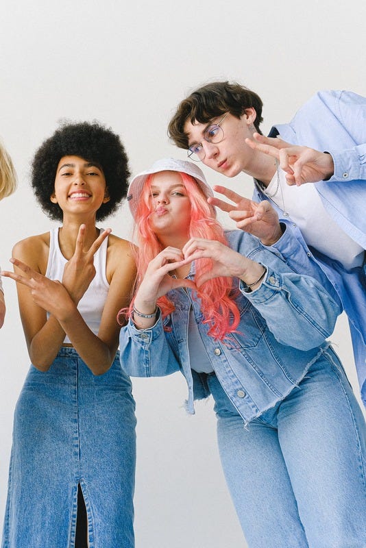 Three people posing for the camera with peace signs (two fingers raised) and a heart shape with both hands