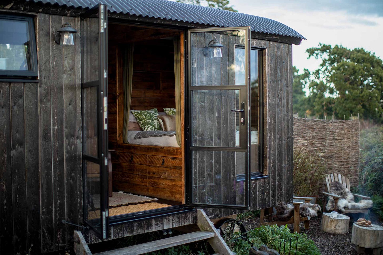 Shepherds hut with doors swung open set within a private outside enclosure