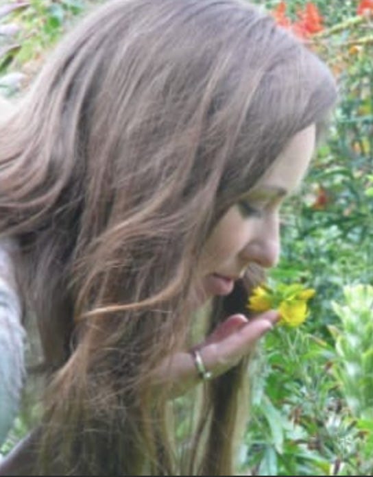 Photo of poet Lisa Stice in profile sniffing a flower