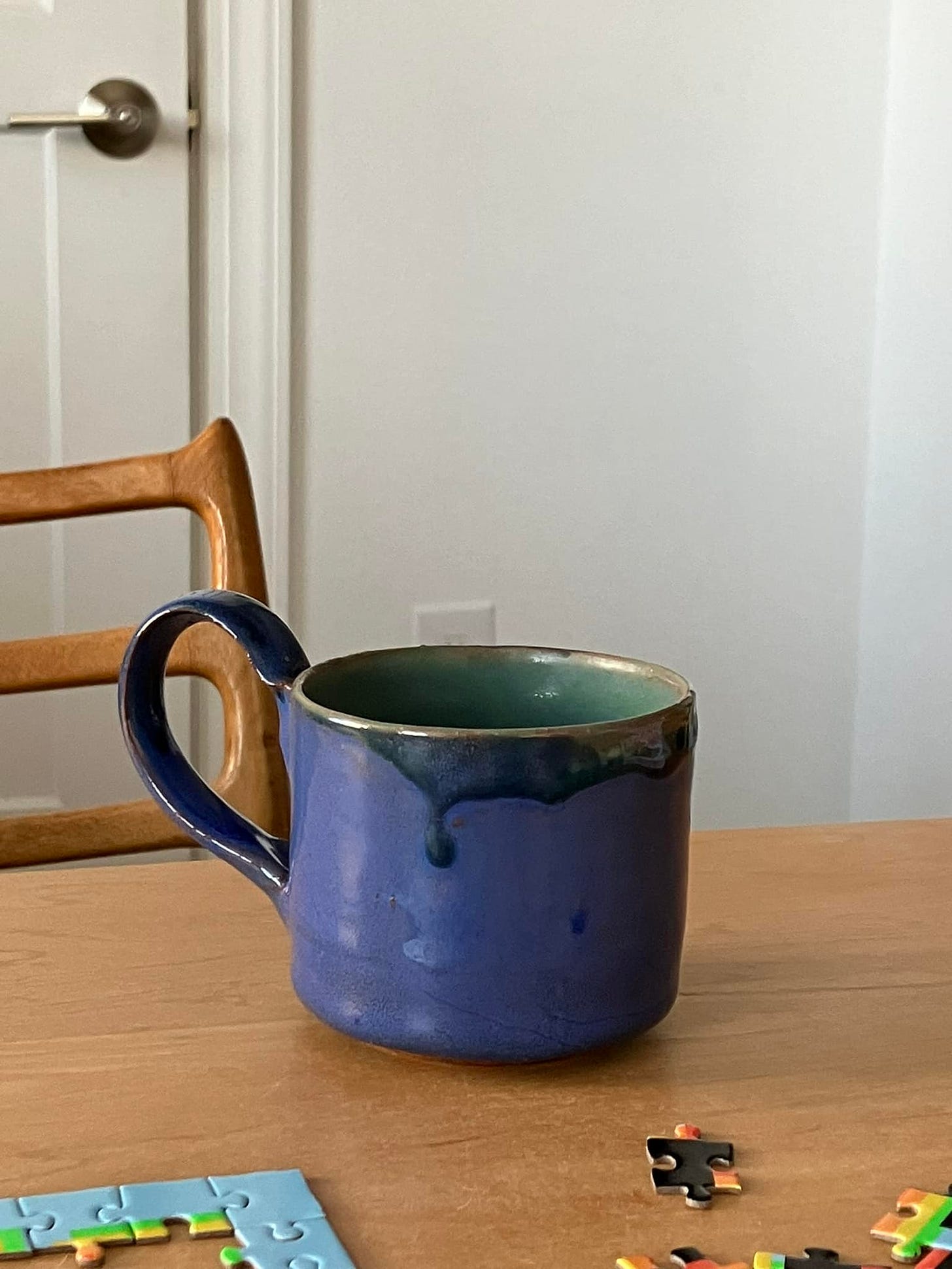 Coffee cup with an elaborate handle on a tabletop, in perwinkle and other blues and greens