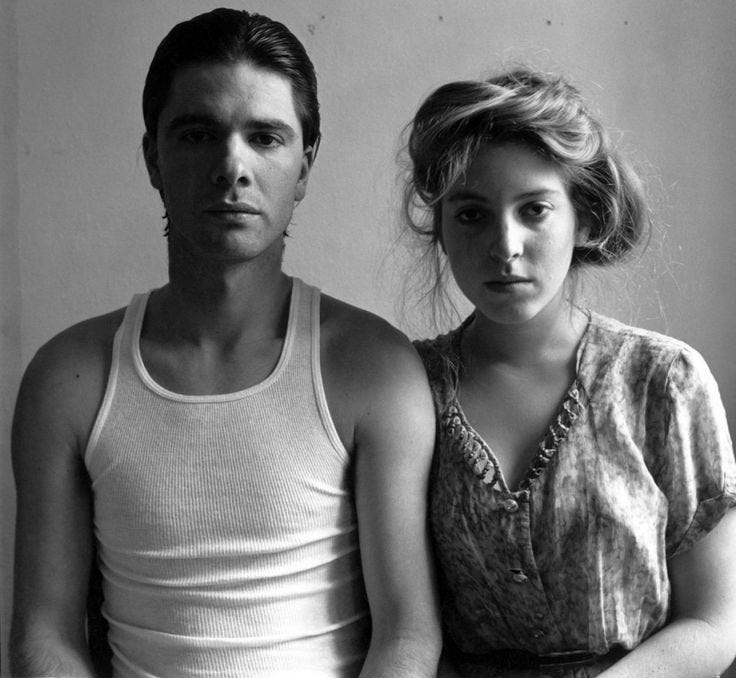 Francesca Woodman and and Benjamin P. Moore. The couple face us like the 1940’s farming couple — only Moore wears his hair in a slick black quiff and dons a taut white vest. Woodman wears a floral dress and has her hair in a pouf like a Gibson Girl. They are both contemporary and anachronistic (this is the 1970's). Both have very solemn faces as they stare out at us in this black and white image.
