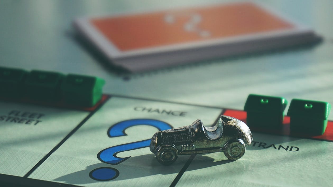 Free A close-up of a Monopoly board game featuring a silver car token and chance card. Stock Photo