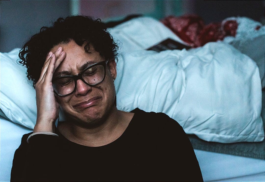 person crying beside bed