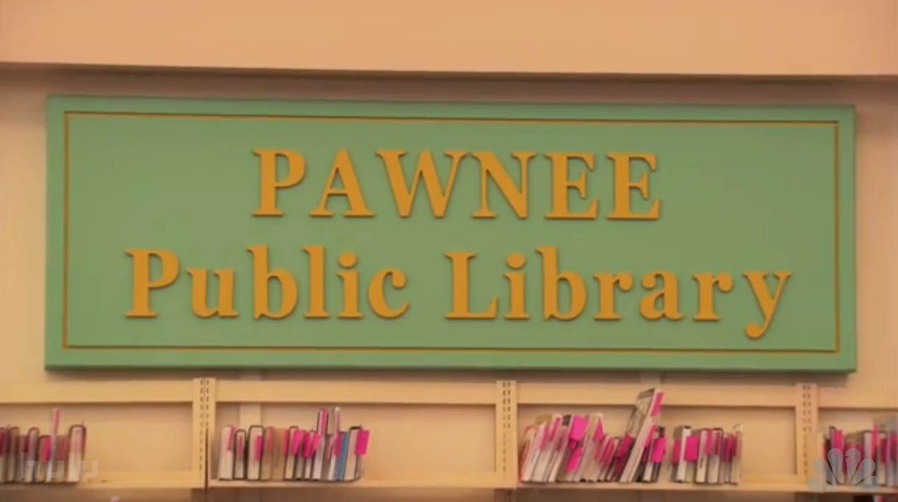 A green and yellow sign reads "Pawnee Public Library." Underneath it is the top of a bookshelf with a few books on it.