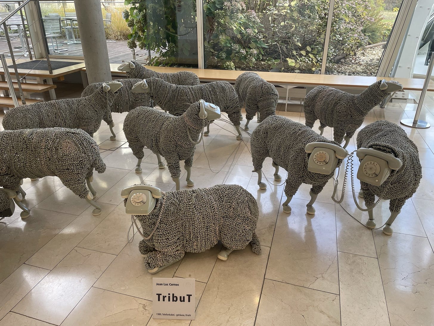 sculptures of sheep made out of telephone parts, with telephone cord bodies and telephone faces and handset feet