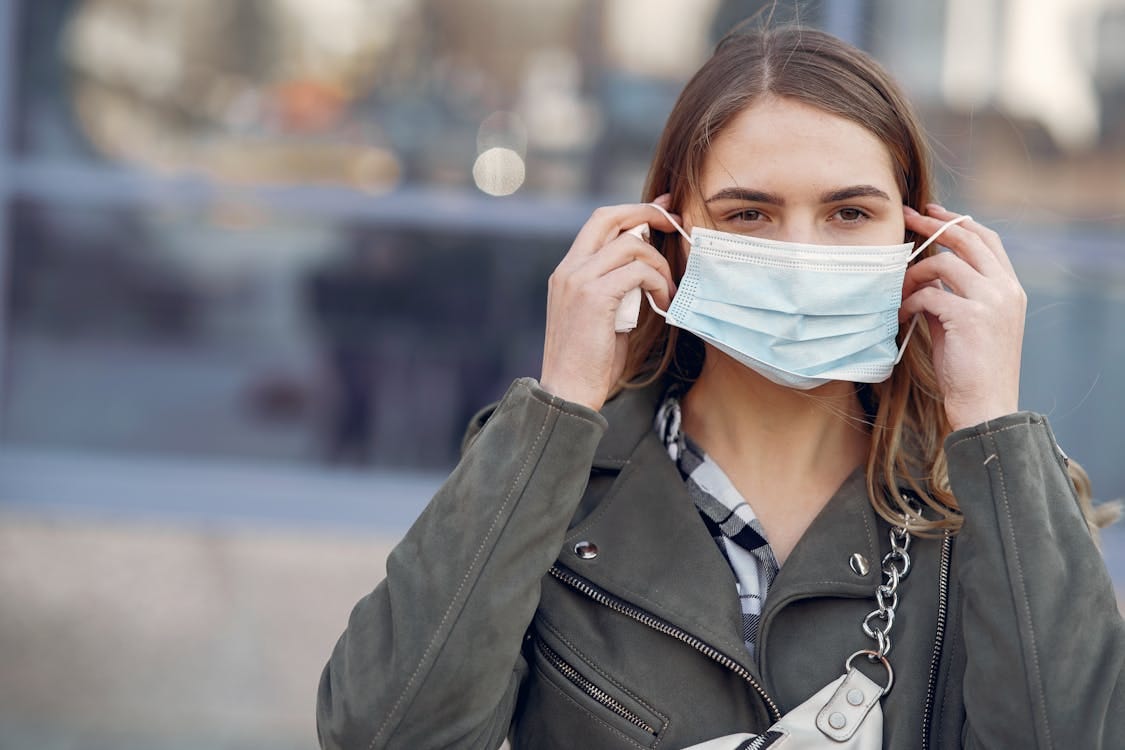 Free Young woman wearing a face mask outdoors for health protection. Stock Photo