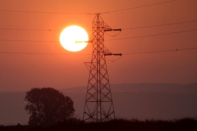 The sun rises behind a tower carrying electrical lines in Suisun City, California.