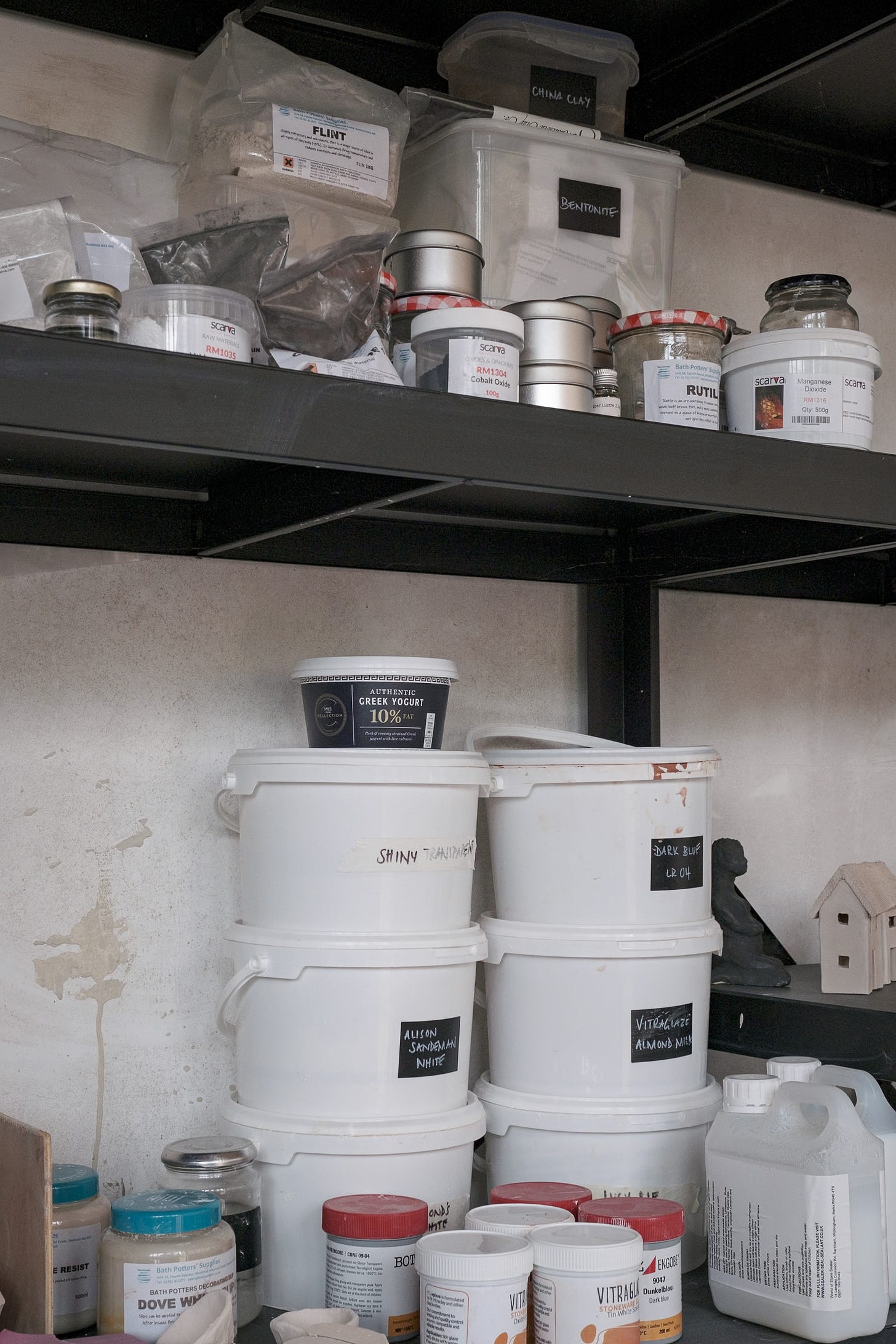 Pottery glazing supplies on black metal shelves