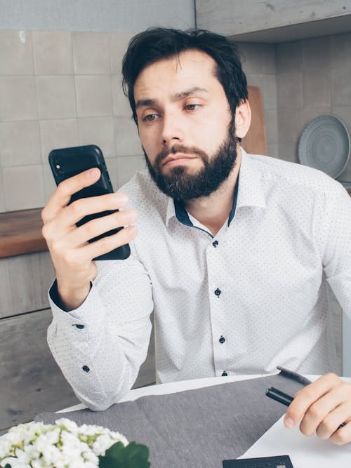 Free Man in White and Black Polka Dot Dress Shirt Holding Black Smartphone Stock Photo