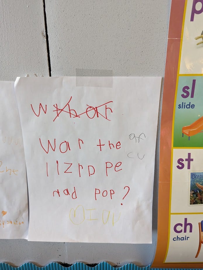 A white piece of paper with red kid handwriting on it that says "war the lizrd pe nad pop?" which I assume means "where does the lizard pee and poop?"