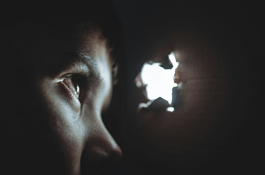 Child looking through a hole at the light.