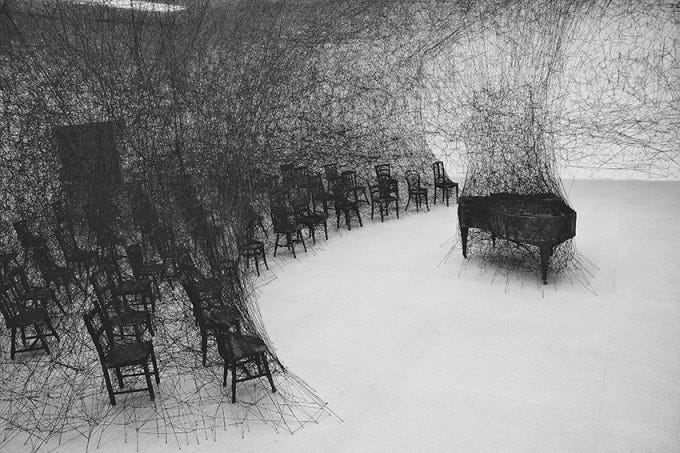 塩田千春《静けさの中で》2008年　焼けたピアノ、焼けた椅子、黒毛糸
 展示風景：「存在様態」パスクアートセンター(スイス、ビール／ビエンヌ)2008年
 撮影：Sunhi Mang