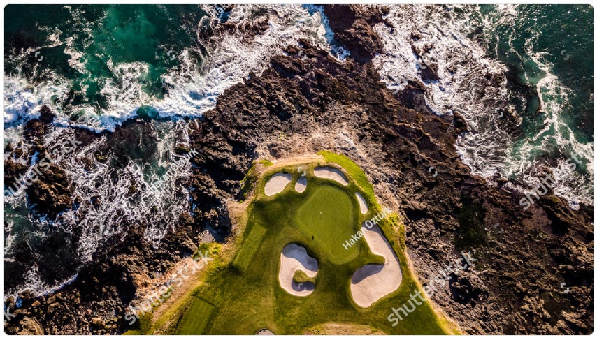 Aerial view of a coastal golf hole with a green perched on a rocky cliff, surrounded by crashing waves and rugged coastline.