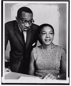 Two Black scientists sit together while conducting their research.