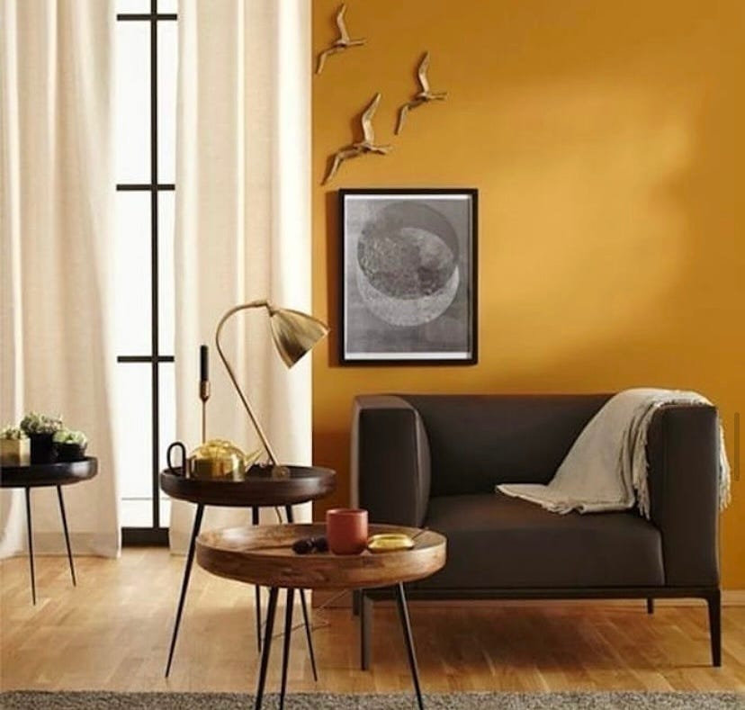 golden painted feature wall with brown leather chair in front