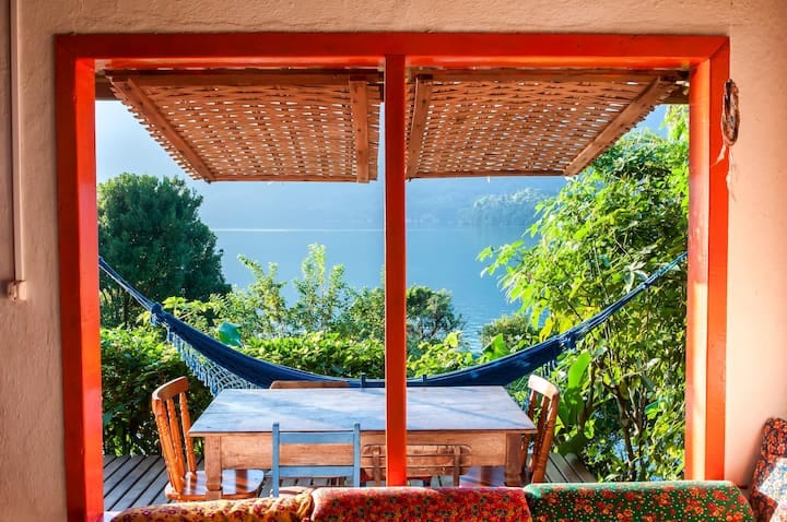 Vista da sala de estar, mesa de jantar no deck externo e vista para o mar
