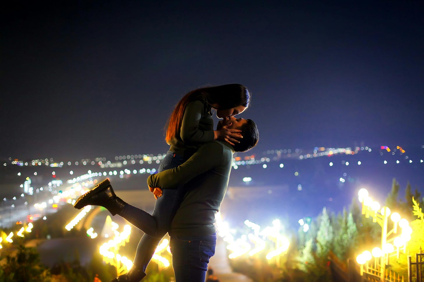 Man and woman embracing above city lights