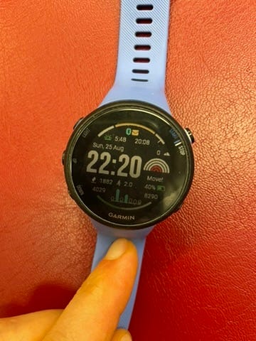 A purple Garmin watch on a red background. Amidst various metrics is the exhortation to "Move!"