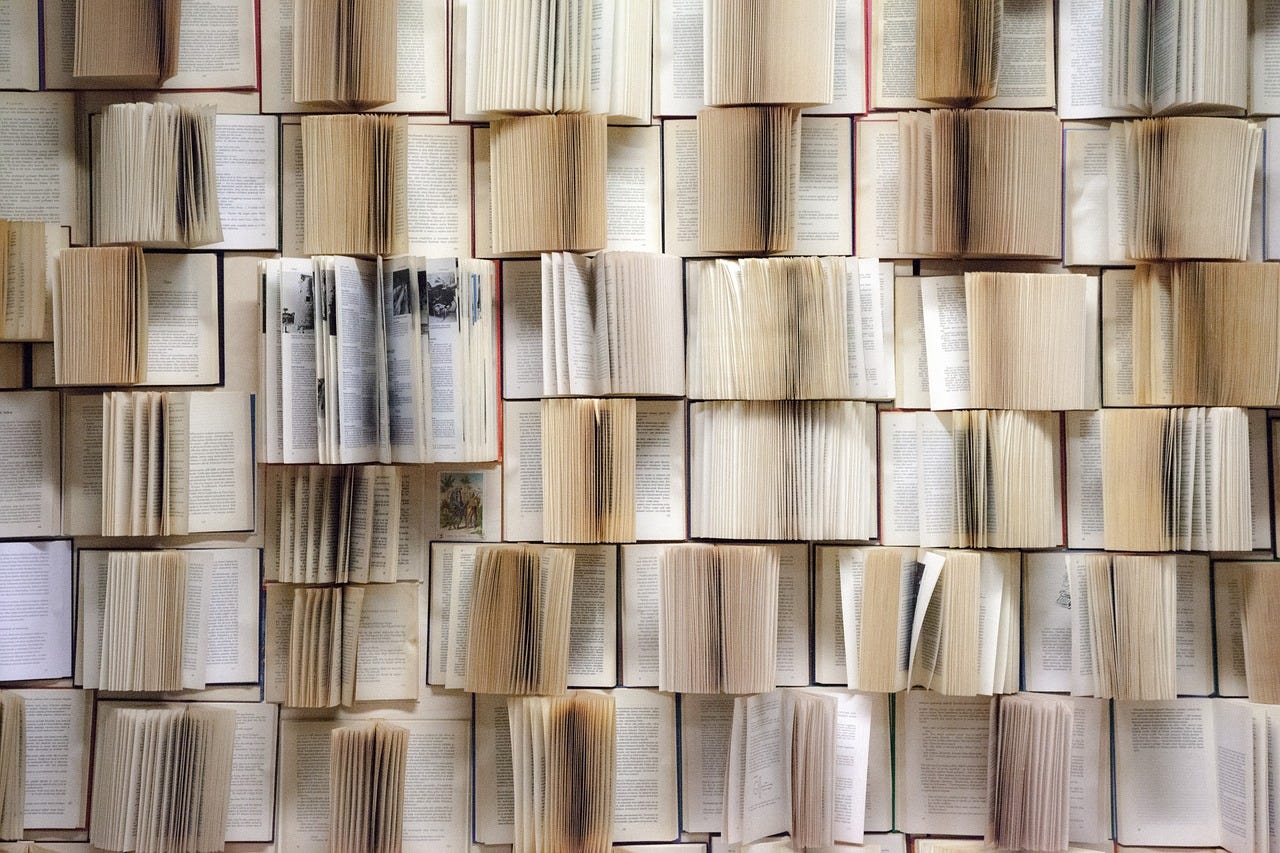 A photo of dozens of books with their pages open.