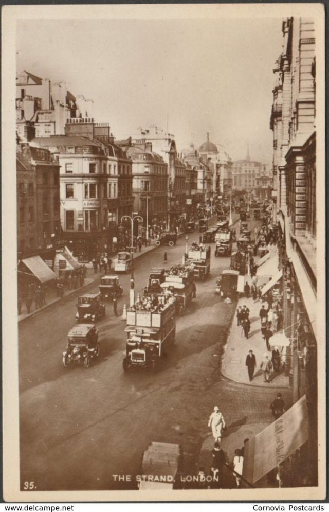 fotografia amarelada da rua Strand, em Londres do alto. Na imagem aparecem uma longa avenida com carros, ônibus e postes no meio dela, nas margens dos dois lados as calçadas com pessoas caminhando, prédios e toldos.