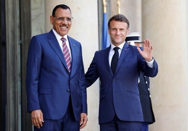 The French leader, Emmanuel Macron, stands with Mohamed Bazoum, Niger’s deposed leader, both dressed in blue suits. 