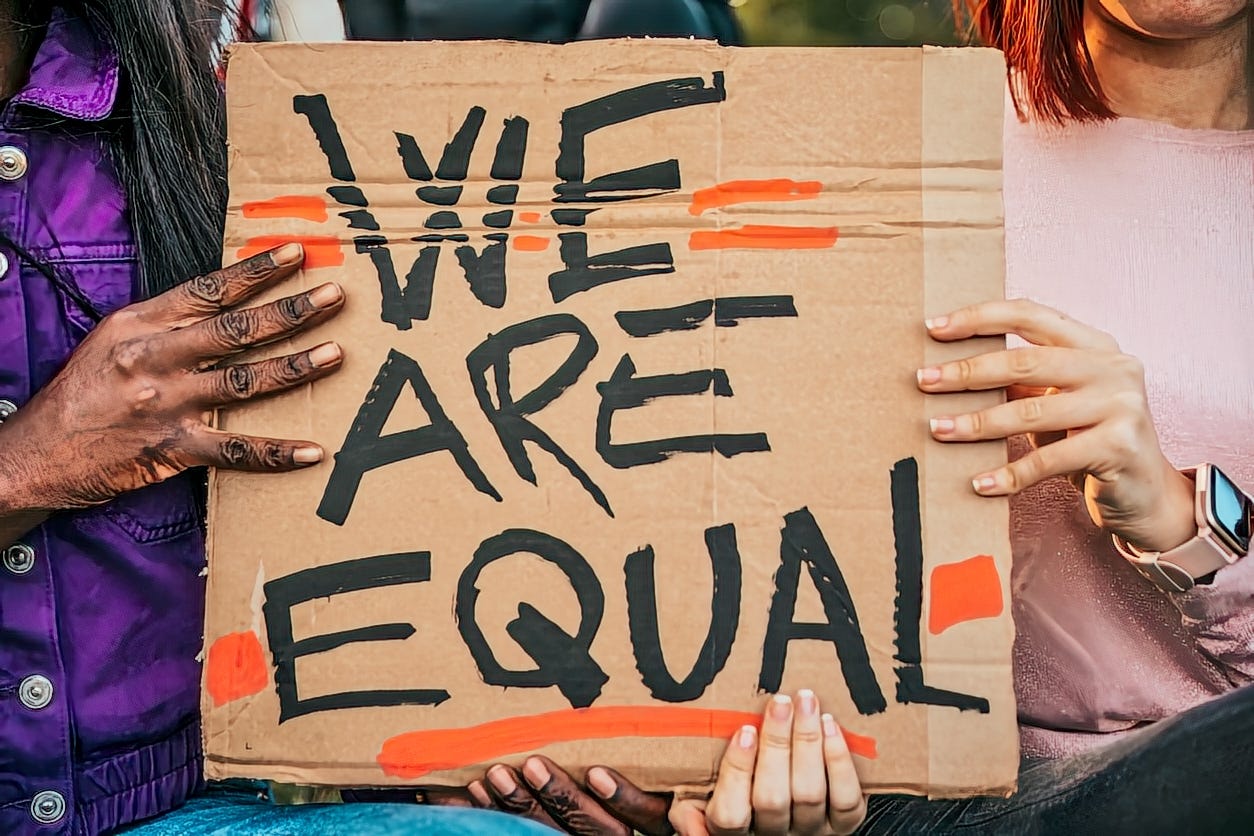 Hands holding sign saying "We are equal"