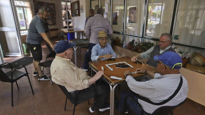 Varias personas mayores juegan al dominó en un hogar del jubilado.