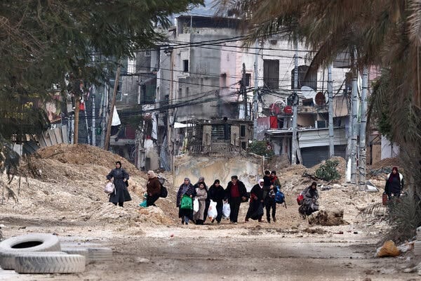 Palestinians carrying bags with their belongings walk down a road during an Israeli raid.