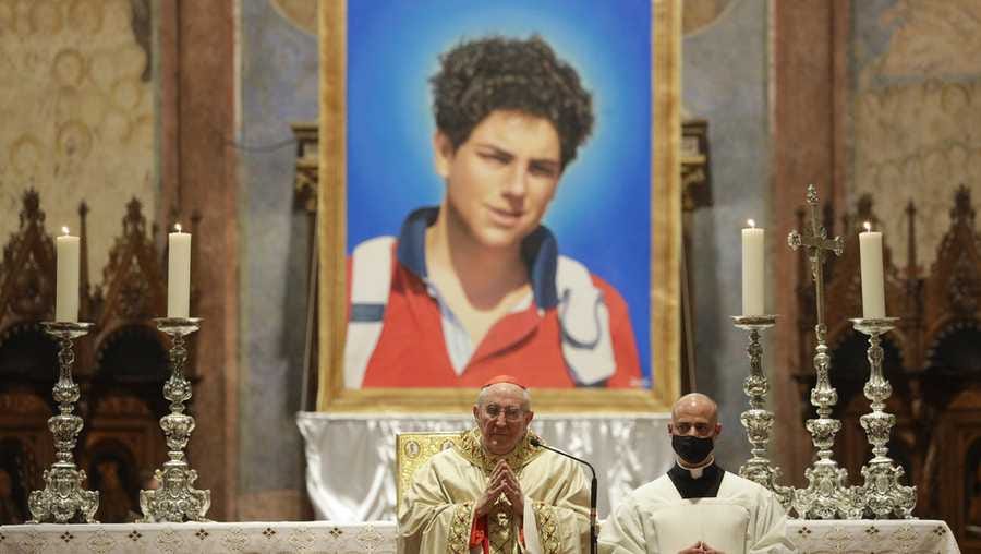 FILE - An image of 15-year-old Carlo Acutis, an Italian boy who died in 2006 of leukemia, is seen during his beatification ceremony celebrated by Cardinal Agostino Vallini, center, in the St. Francis Basilica, in Assisi, Italy, on Oct. 10, 2020. Pope Francis has paved the way for the canonization of the first saint of the millennial generation on Thursday, attributing a second miracle to a 15-year-old Italian computer whiz who died of leukemia in 2006. Carlo Acutis, born on May 3, 1991, in London and then moved with his Italian parents to Milan as a child, was the youngest contemporary person to be beatified by Francis in Assisi in 2020. (AP Photo/Gregorio Borgia, File)